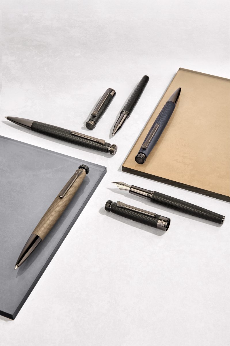 Writing instruments across a desk pad and notebook — Festina