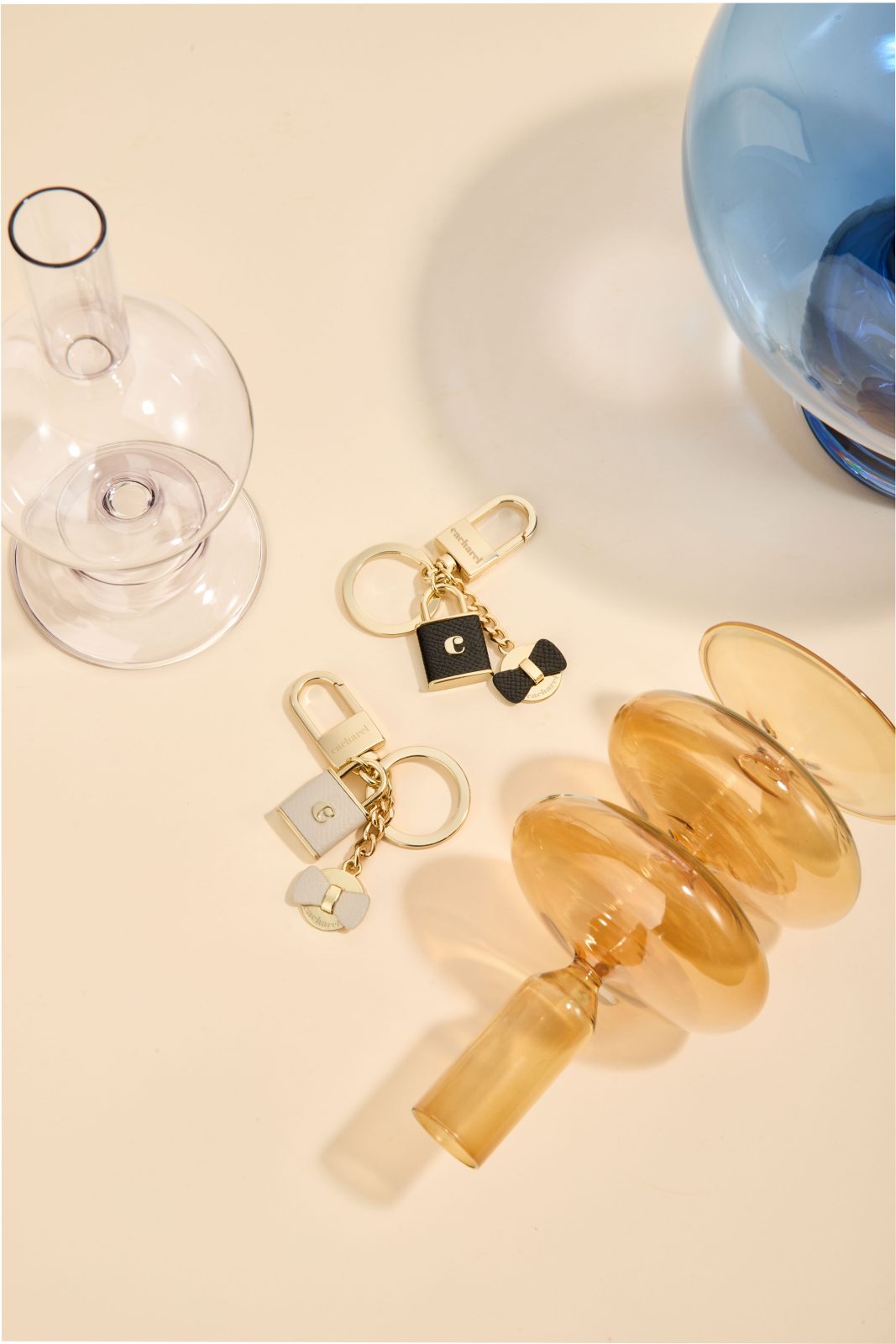 Keyrings and desk pieces in a warm amber still life — Cacharel