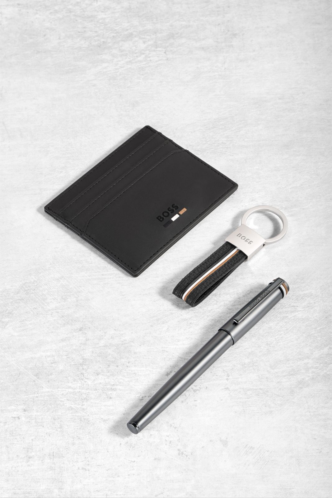 Card holder, keyring and pen laid out on stone — Hugo Boss